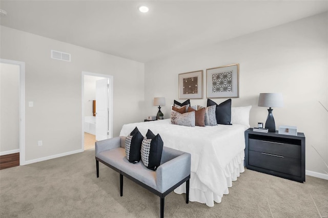 bedroom featuring connected bathroom and light colored carpet