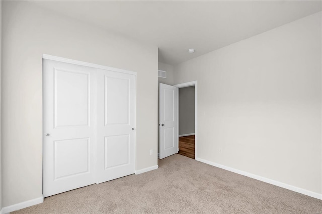 unfurnished bedroom with light carpet and a closet