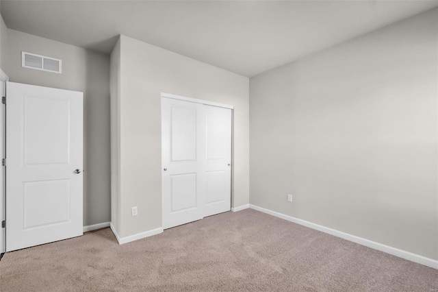 unfurnished bedroom featuring a closet and light colored carpet