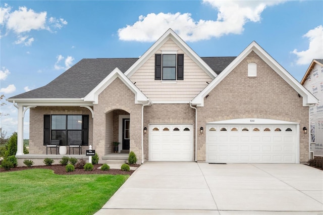 view of front of property featuring a garage, a porch, and a front yard