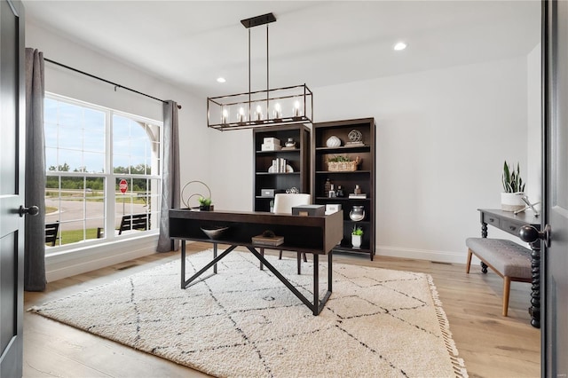 home office featuring a notable chandelier, plenty of natural light, and light wood-type flooring