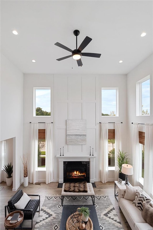 living room featuring light wood-type flooring, ceiling fan, and a healthy amount of sunlight