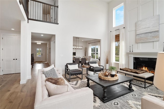 living room with a wealth of natural light, light hardwood / wood-style floors, and a high ceiling