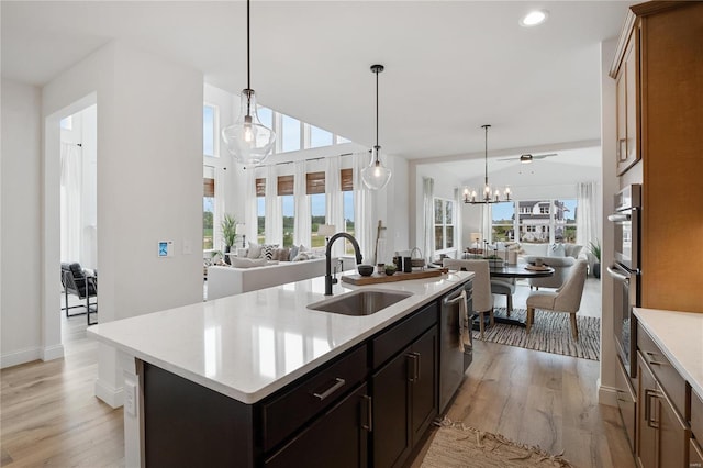 kitchen featuring a center island with sink, sink, stainless steel dishwasher, ceiling fan, and decorative light fixtures