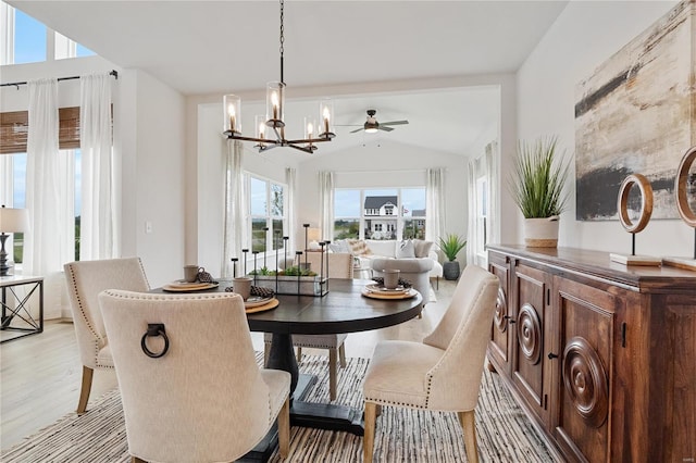 dining space with ceiling fan with notable chandelier, light hardwood / wood-style floors, a healthy amount of sunlight, and vaulted ceiling