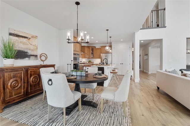 dining room with light hardwood / wood-style flooring and a chandelier