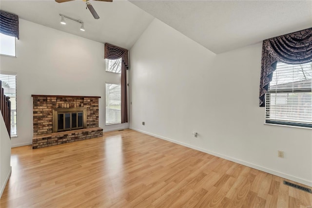 unfurnished living room featuring vaulted ceiling, a brick fireplace, light hardwood / wood-style floors, and ceiling fan