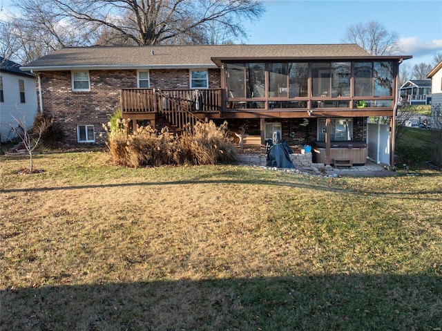 rear view of property featuring a hot tub, a wooden deck, a sunroom, and a lawn