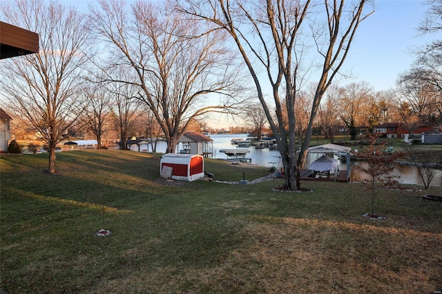 yard at dusk with a storage unit and a water view