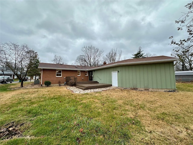 rear view of property with a wooden deck and a lawn