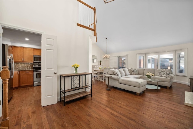 living room with high vaulted ceiling, dark hardwood / wood-style floors, and an inviting chandelier