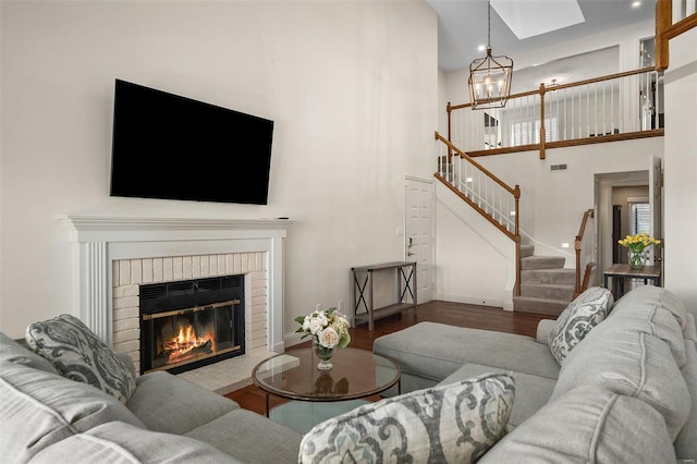 living room with a skylight, a notable chandelier, a towering ceiling, a fireplace, and wood-type flooring