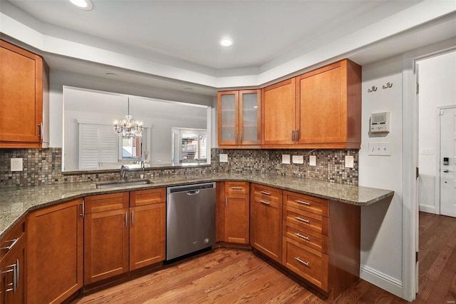 kitchen featuring dishwasher, a notable chandelier, stone counters, pendant lighting, and sink