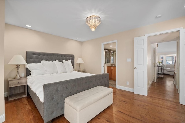 bedroom with hardwood / wood-style flooring, ensuite bath, and an inviting chandelier