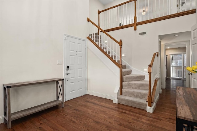 entryway featuring a towering ceiling and dark hardwood / wood-style floors