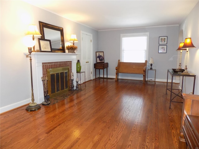 sitting room with wood-type flooring, a brick fireplace, and ornamental molding