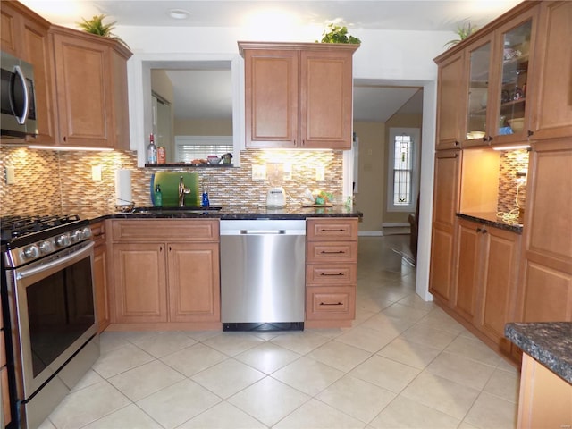 kitchen featuring tasteful backsplash, sink, dark stone counters, and appliances with stainless steel finishes