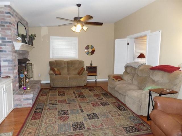 living room featuring a brick fireplace, light hardwood / wood-style flooring, and ceiling fan