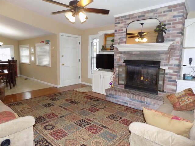 living room featuring hardwood / wood-style flooring, ceiling fan, and a brick fireplace