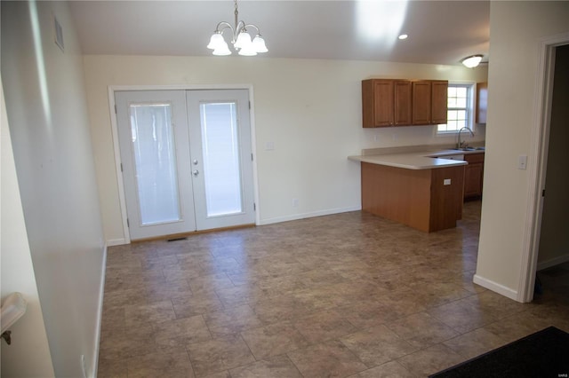 kitchen featuring kitchen peninsula, french doors, sink, pendant lighting, and a notable chandelier