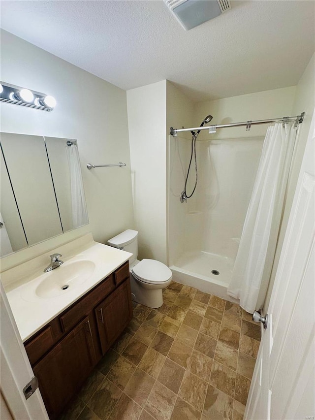 bathroom featuring curtained shower, vanity, a textured ceiling, and toilet