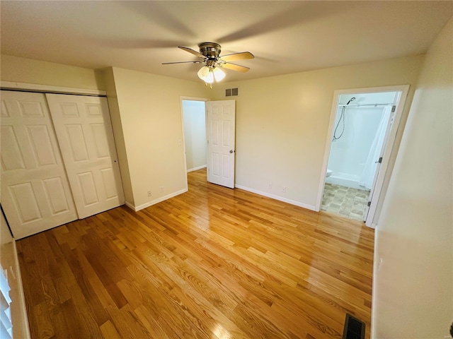 unfurnished bedroom with ceiling fan, ensuite bathroom, and light wood-type flooring