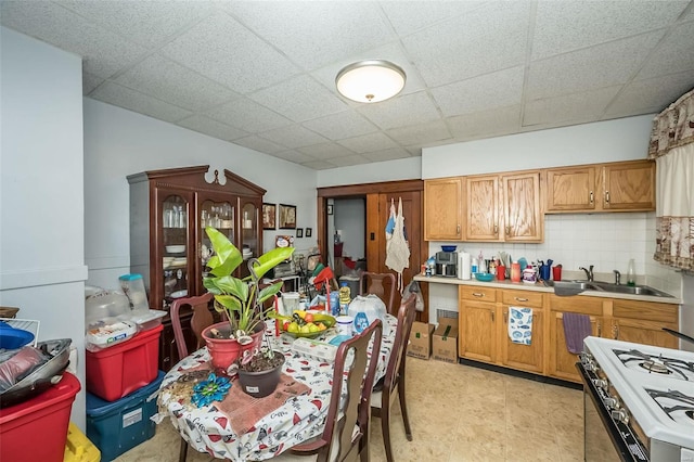 kitchen with a paneled ceiling, decorative backsplash, white range with gas stovetop, and sink