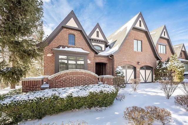 english style home featuring a garage and brick siding