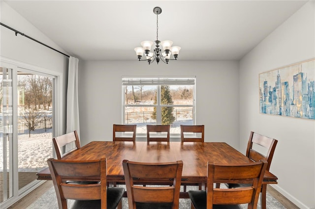 dining room with a wealth of natural light, hardwood / wood-style floors, and an inviting chandelier