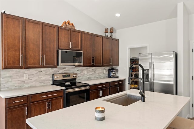 kitchen featuring decorative backsplash, stainless steel appliances, vaulted ceiling, a kitchen island with sink, and sink