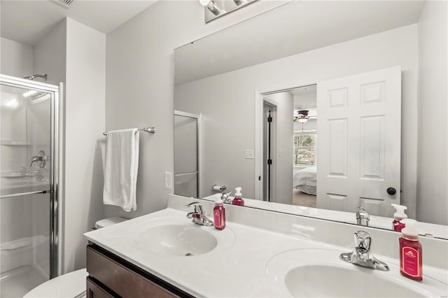 bathroom featuring vanity, toilet, a shower with door, and ceiling fan