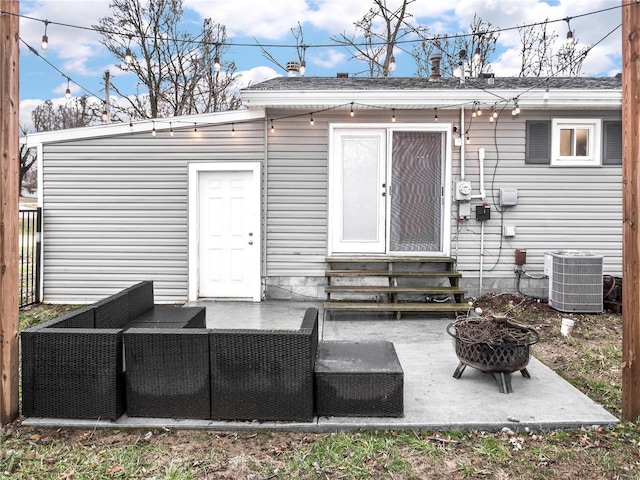 back of property with central AC unit and an outdoor fire pit