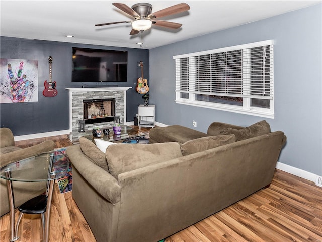 living room with hardwood / wood-style floors, ceiling fan, and a fireplace