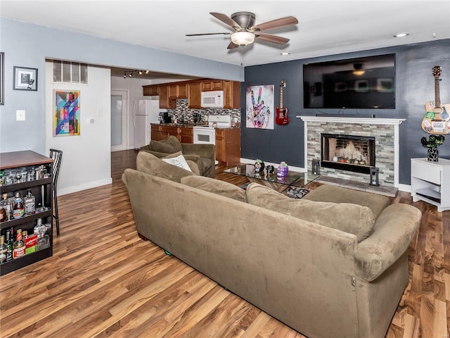 living room with hardwood / wood-style floors, ceiling fan, and a fireplace