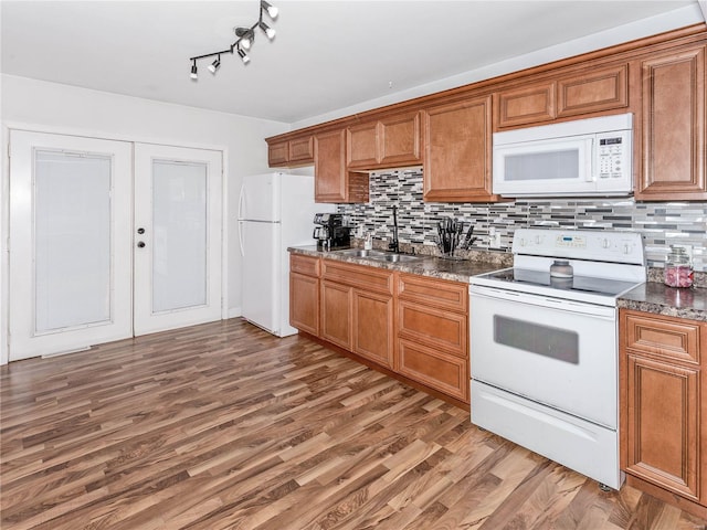 kitchen with wood-type flooring, white appliances, backsplash, and sink