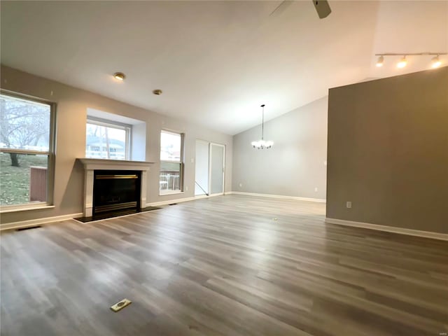 unfurnished living room with hardwood / wood-style floors, ceiling fan with notable chandelier, track lighting, and lofted ceiling