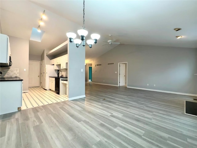 kitchen with backsplash, ceiling fan with notable chandelier, vaulted ceiling, white fridge, and white cabinetry