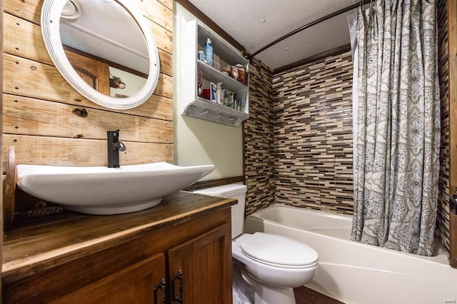 full bathroom featuring shower / bath combo with shower curtain, vanity, a textured ceiling, and toilet