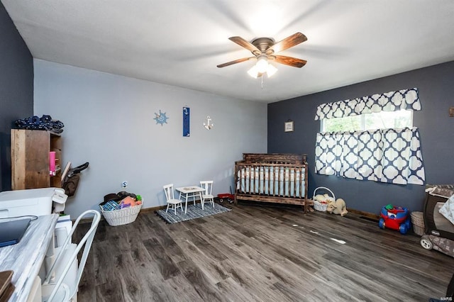 bedroom featuring hardwood / wood-style floors, ceiling fan, and a nursery area