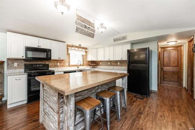 kitchen featuring a center island, white cabinetry, lofted ceiling, and black appliances