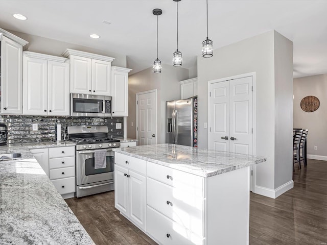 kitchen with white cabinetry, dark hardwood / wood-style flooring, decorative light fixtures, a kitchen island, and appliances with stainless steel finishes