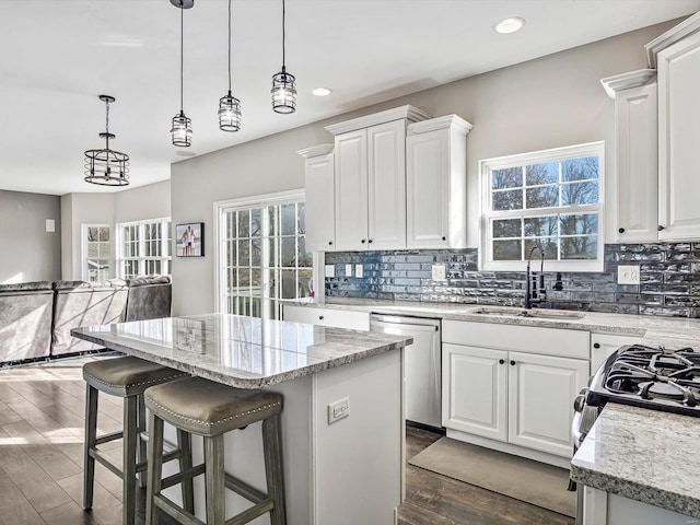 kitchen with a center island, white cabinetry, stainless steel dishwasher, and sink