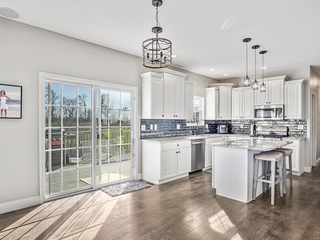 kitchen with white cabinets, a center island, hanging light fixtures, and appliances with stainless steel finishes