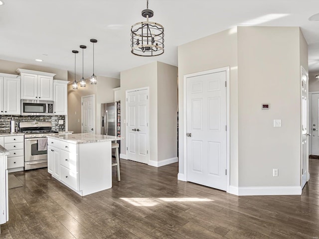 kitchen with a center island, light stone counters, decorative light fixtures, white cabinets, and appliances with stainless steel finishes