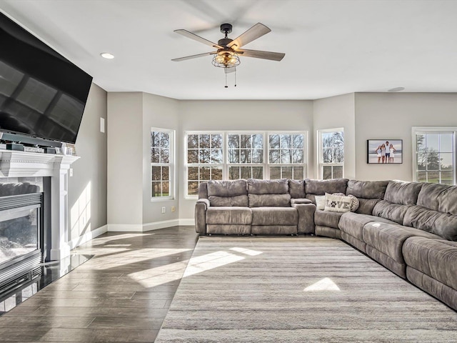 living room with a high end fireplace, light hardwood / wood-style flooring, ceiling fan, and a healthy amount of sunlight