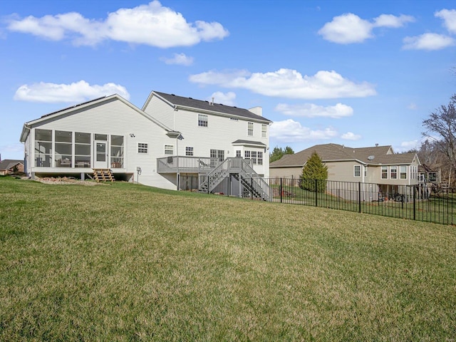 rear view of property featuring a yard, a sunroom, and a wooden deck