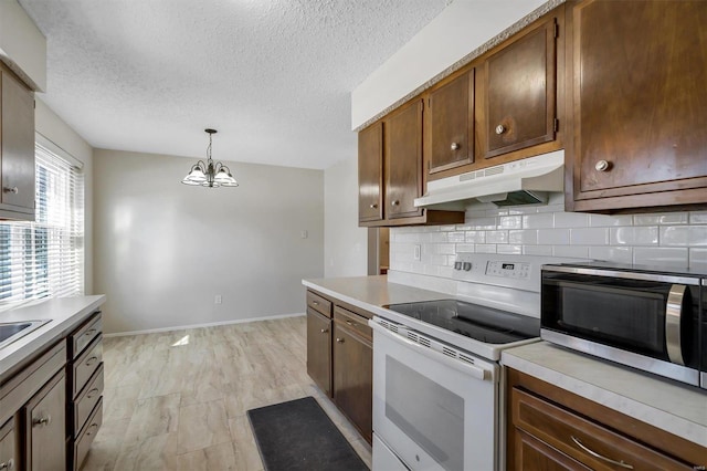 kitchen featuring a textured ceiling, tasteful backsplash, white range with electric stovetop, hanging light fixtures, and a chandelier