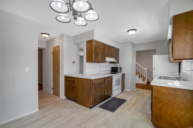 kitchen featuring white appliances, a textured ceiling, a notable chandelier, and sink