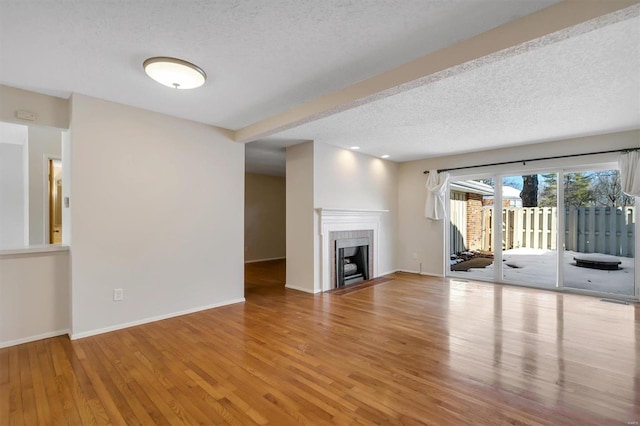 unfurnished living room with wood-type flooring and a textured ceiling