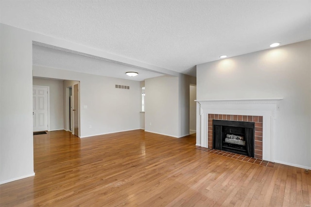 unfurnished living room featuring a textured ceiling, light wood-type flooring, and a fireplace